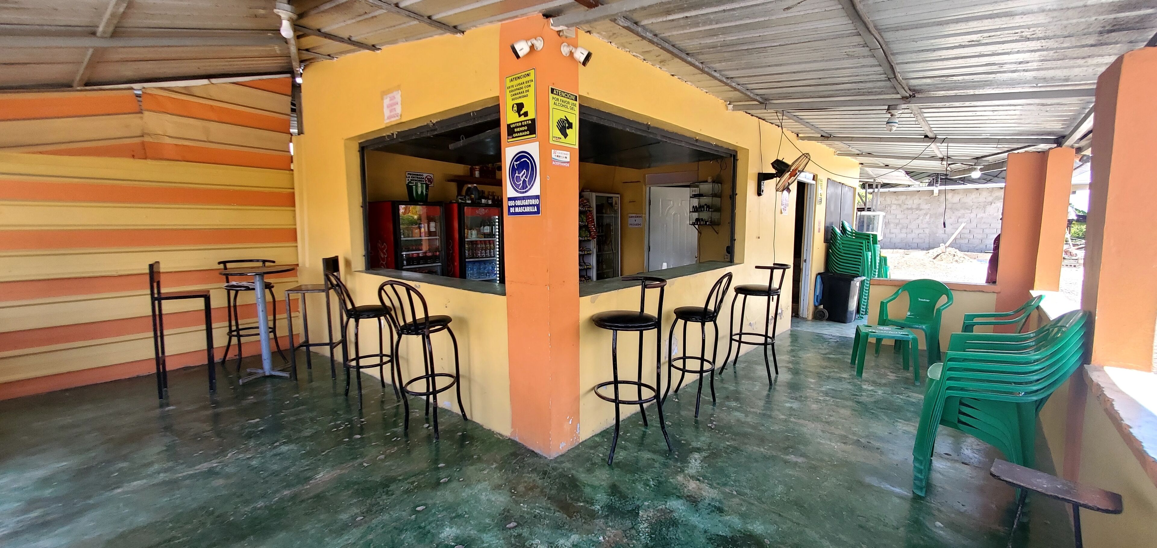 A small bar area with a counter and stools, a refrigerator, and a door leading to another room.