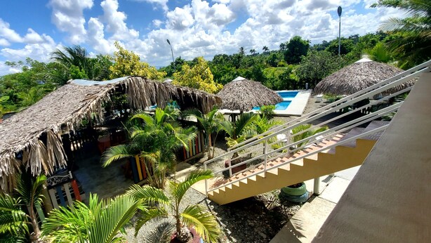 Un resort tropical con estructuras de techo de paja, una piscina y una escalera que lleva a un nivel superior.