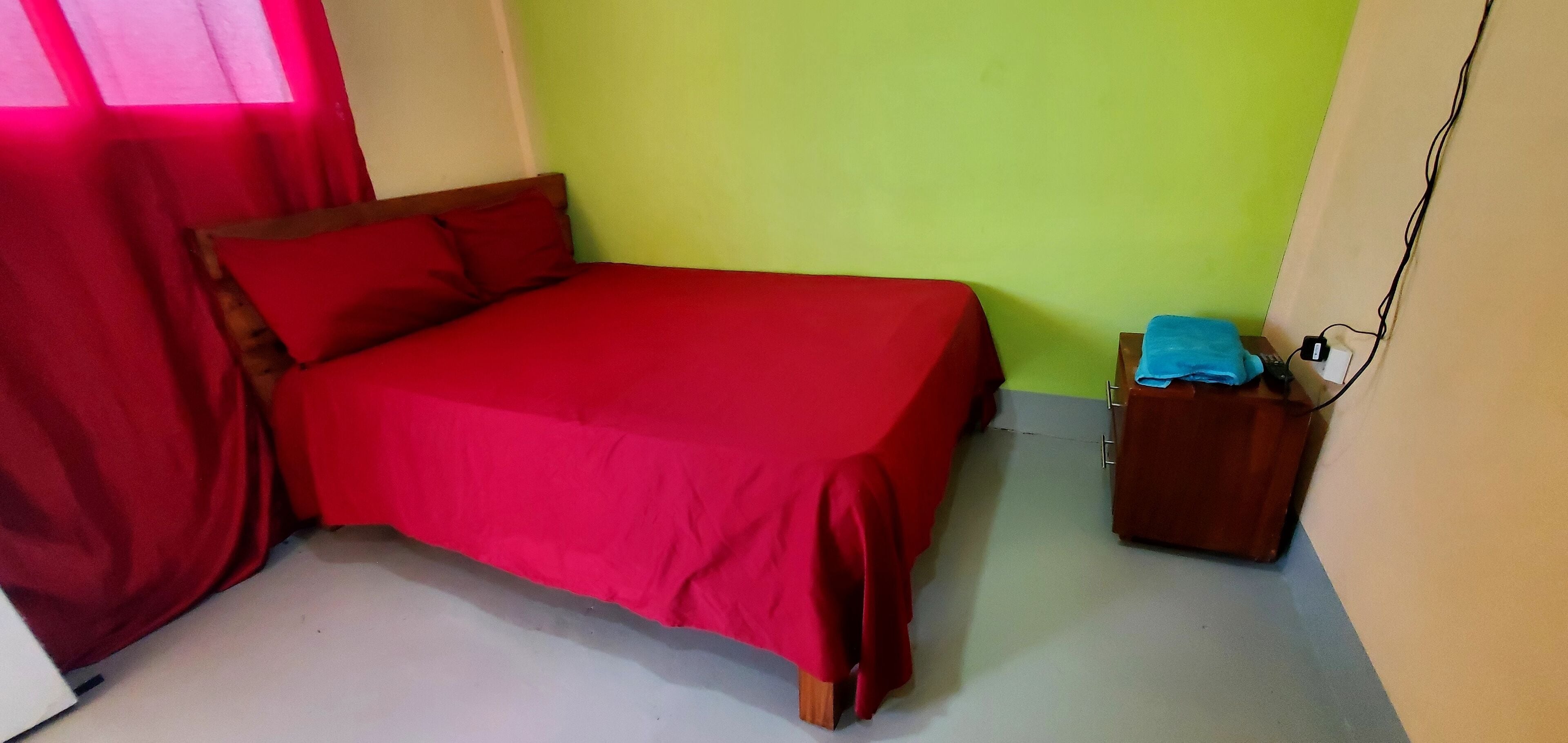 Une chambre avec un lit, une table de chevet et une fenêtre avec des rideaux.