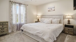 Una camera da letto con un letto grande, due comodini con lampade, una cassettiera e un ventilatore a soffitto.