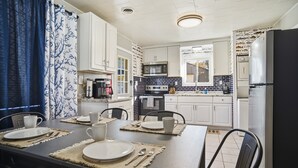 Una cocina moderna con armarios blancos, encimera negra y refrigerador de acero inoxidable.
