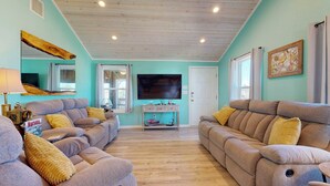 A living room with two sofas, a coffee table, a TV, and a wooden ceiling. - Pet Friendly, Golf Cart Access, Old Town Location (Port Aransas)