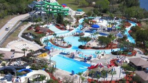 Ein Luftbild eines Wasserparks mit einem großen Pool, mehreren Rutschen und einer wellenförmigen Wasserbahn.