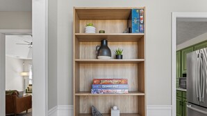 Une bibliothèque en bois avec des livres, une plante et des paniers.
