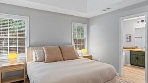 Une chambre à coucher avec un lit, des tables de chevet et une fenêtre avec des stores.