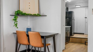 A dining area with a table and two chairs, a refrigerator, and a shelf with plants. - Luxury Studio Escape - Trails & Views (Sugarloaf)