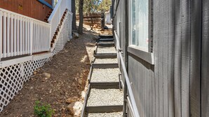 A narrow outdoor pathway leading to a wooden house with a white fence and a wooden deck. - Luxury Studio Escape - Trails & Views (Sugarloaf)