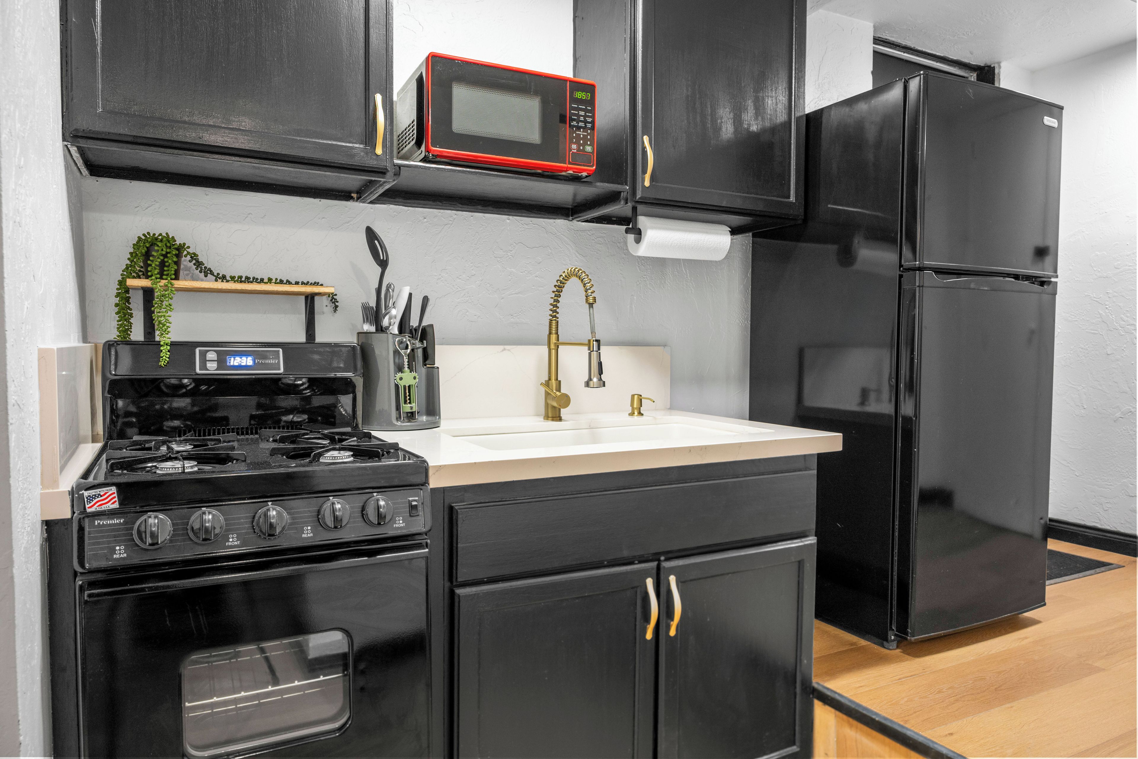 A compact kitchen with a stove, microwave, sink, and refrigerator.