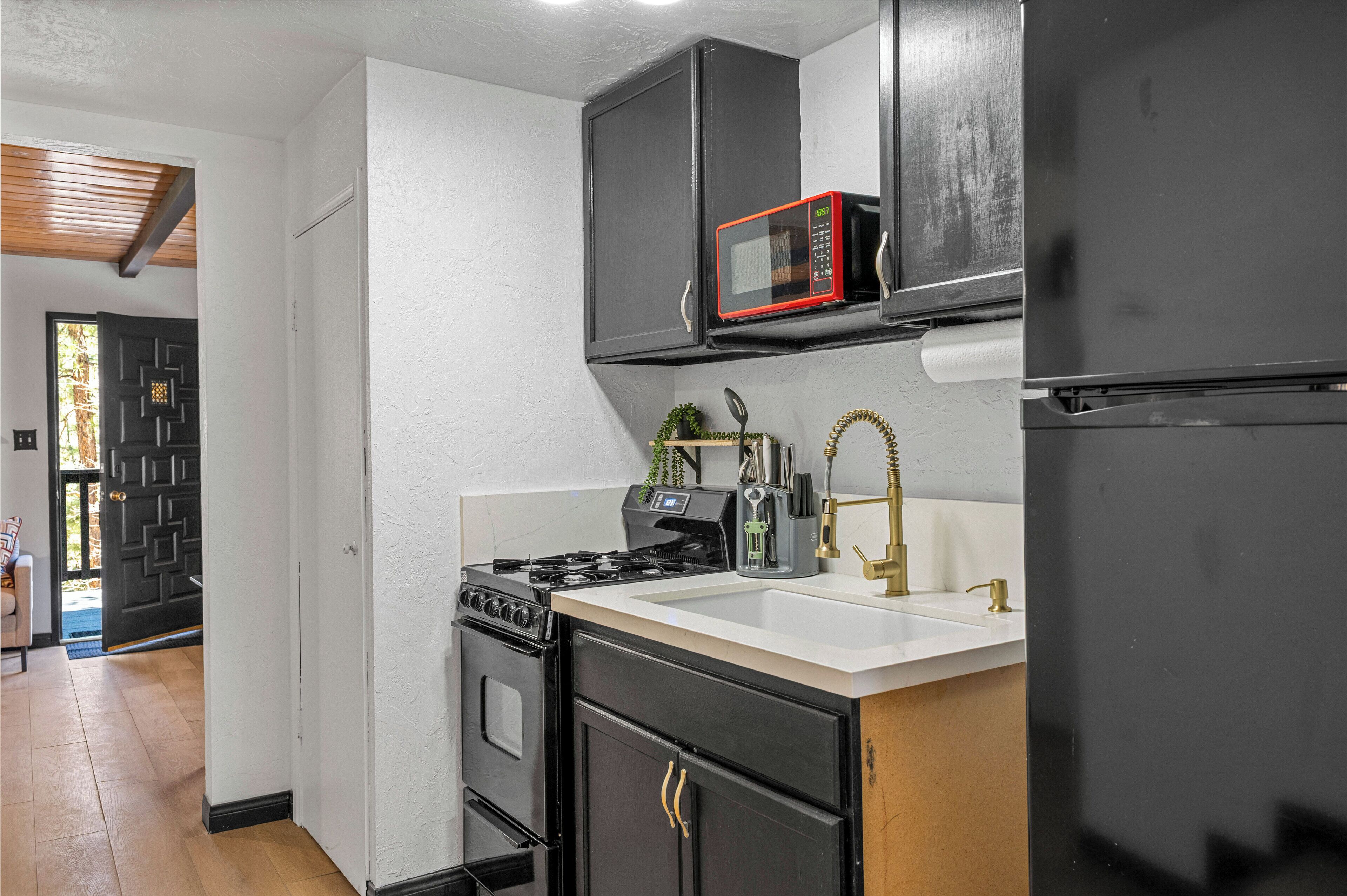 A kitchen with a stove, oven, microwave, sink, and refrigerator.