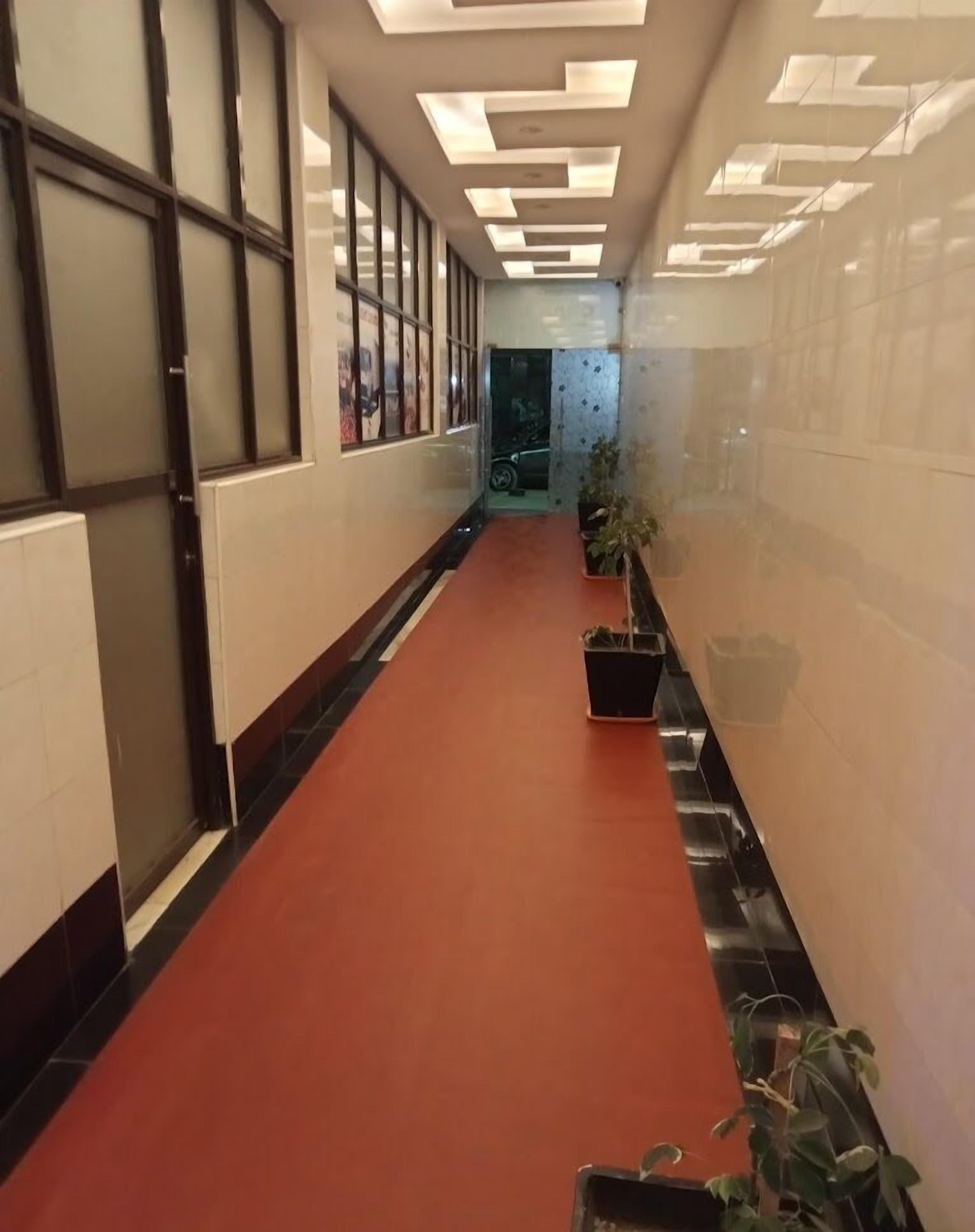 A corridor with a red carpet, glass doors, and a ceiling with recessed lighting.