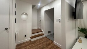 A modern interior with a staircase, white walls, and a flat-screen TV mounted on the wall. - Luxury sweet home (Longueuil)