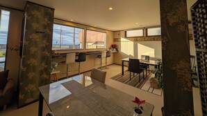 A modern kitchen with a large window, a dining area with a table and chairs, and a view of the outside. - Auberge Suehiro (Minamiboso)