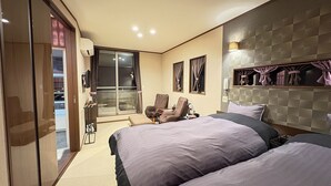 A hotel room with two beds, a massage chair, a desk, and a sliding glass door leading to a balcony. - Auberge Suehiro (Minamiboso)