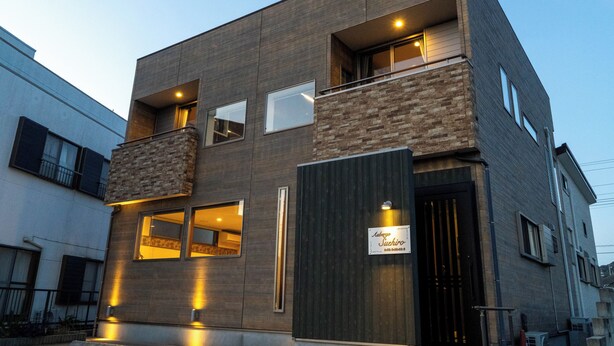 A modern building with a stone facade, multiple windows, and a sign indicating a business establishment. - Auberge Suehiro (Minamiboso)