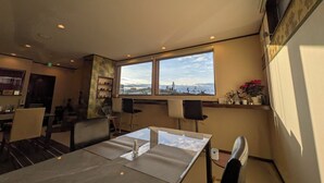 A dining area with a table and chairs, a window with a view, and shelves with items. - Auberge Suehiro (Minamiboso)