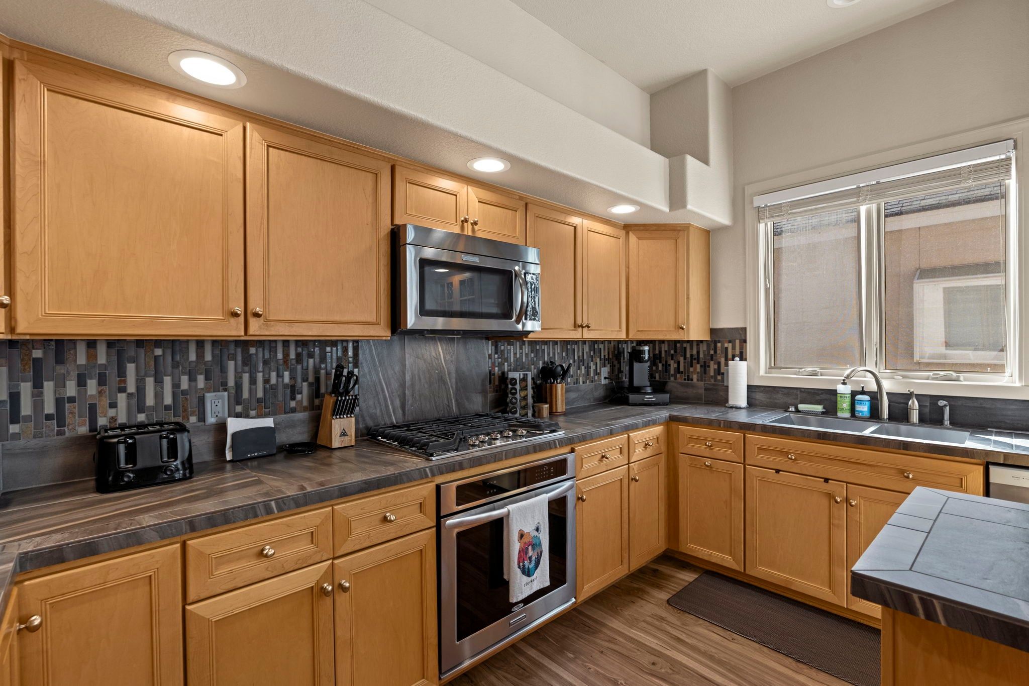 A modern kitchen with wooden cabinets, a stainless steel microwave, a gas stove, and a built-in oven.