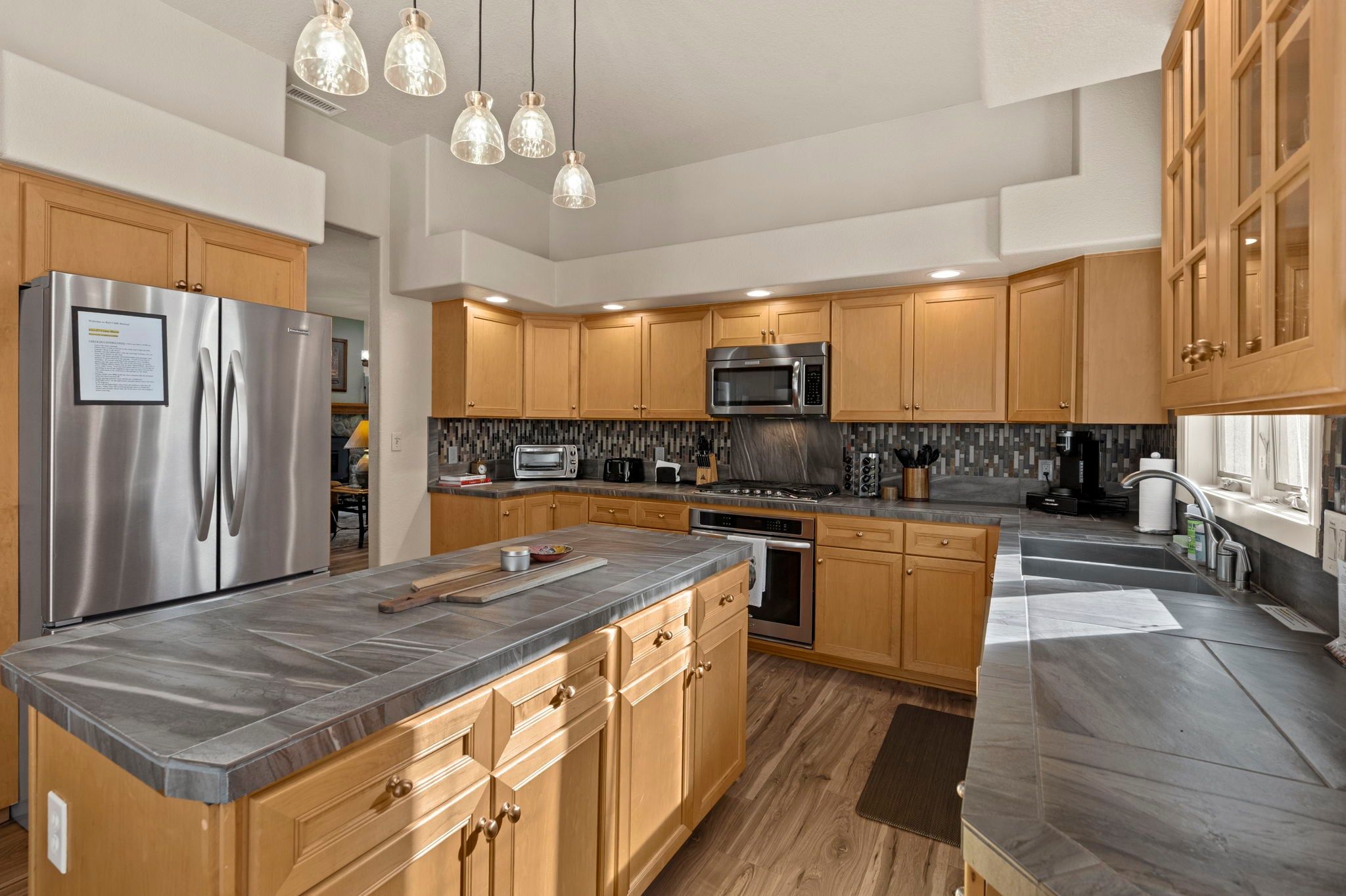 A modern kitchen with stainless steel appliances, wooden cabinets, and a large island.
