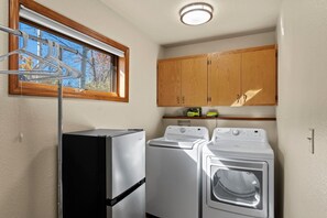 A compact kitchen with a refrigerator, two washing machines, wooden cabinets, and a window with a view of trees. - Golf Course, Hot Spring Close, Dalton Ranch! (Durango)