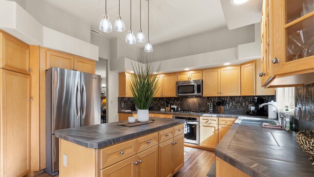 A modern kitchen with wooden cabinets, stainless steel appliances, and a central island.