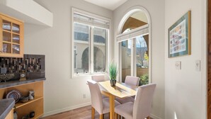 A dining area with a wooden table and four chairs, a potted plant, and a tiled backsplash.
