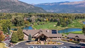 A lodge with a stone facade, a parking lot, and a golf course with a lake.