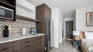 A modern kitchen with a built-in microwave, stainless steel refrigerator, and a patterned backsplash. - The Jardín | Spanish Studio | Foodie Row (Portland)