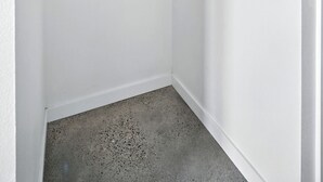 Un placard d’angle avec une tringle à vêtements en bois et un plafond blanc.