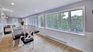A dining area with a wooden table, white chairs, and a vase of flowers.