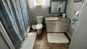 Une salle de bain équipée de toilettes, d’un lavabo, d’un meuble-lavabo et d’un rideau de douche.
