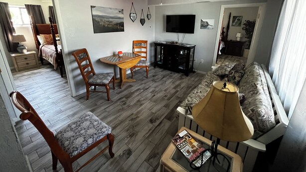 Un salon comprenant un canapé, une table, deux chaises, un téléviseur et un ventilateur de plafond.