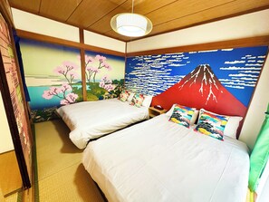 Habitació d'hotel amb dos llits, un mural del Mont Fuji i un sostre d'estil japonès tradicional.