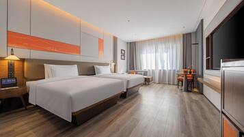 Een moderne hotelkamer met twee bedden, een bureau, een stoel, een televisie en een groot raam met gordijnen.