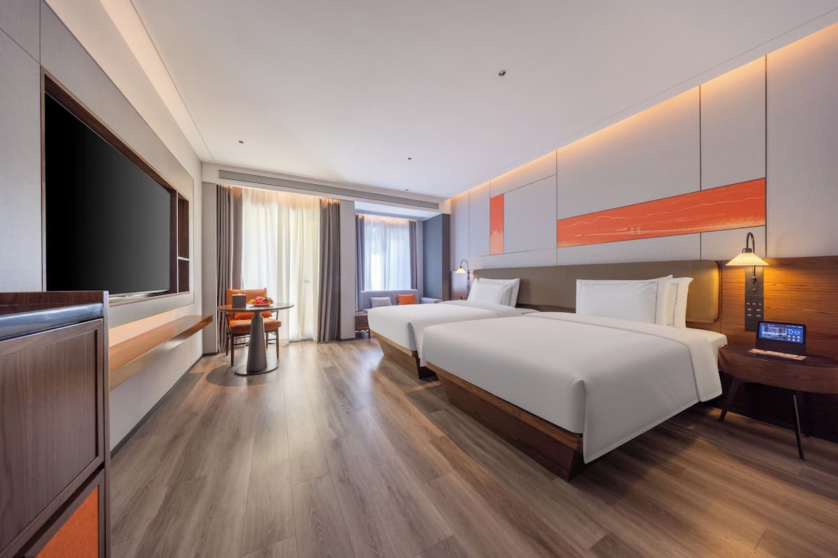 Une chambre d’hôtel avec deux lits, un bureau, une télévision et une vue sur la ville.