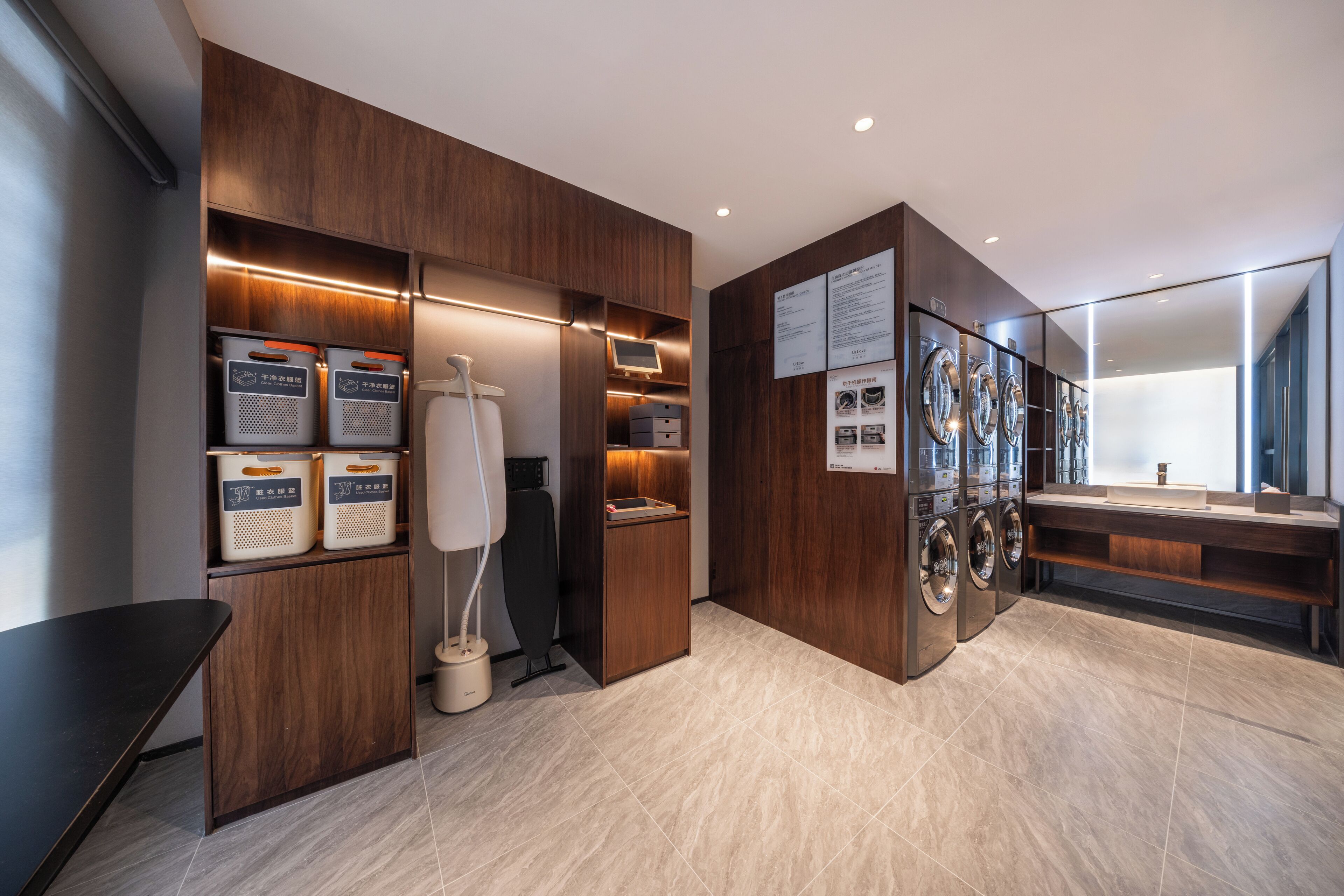 A modern hotel bathroom with wooden cabinetry, a washing machine, and a sink.
