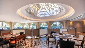 A hotel lobby with a central circular skylight, seating areas, and large windows offering views of the outside. - UrCove by HYATT Zhuhai Gongbei Port (Zhuhai)