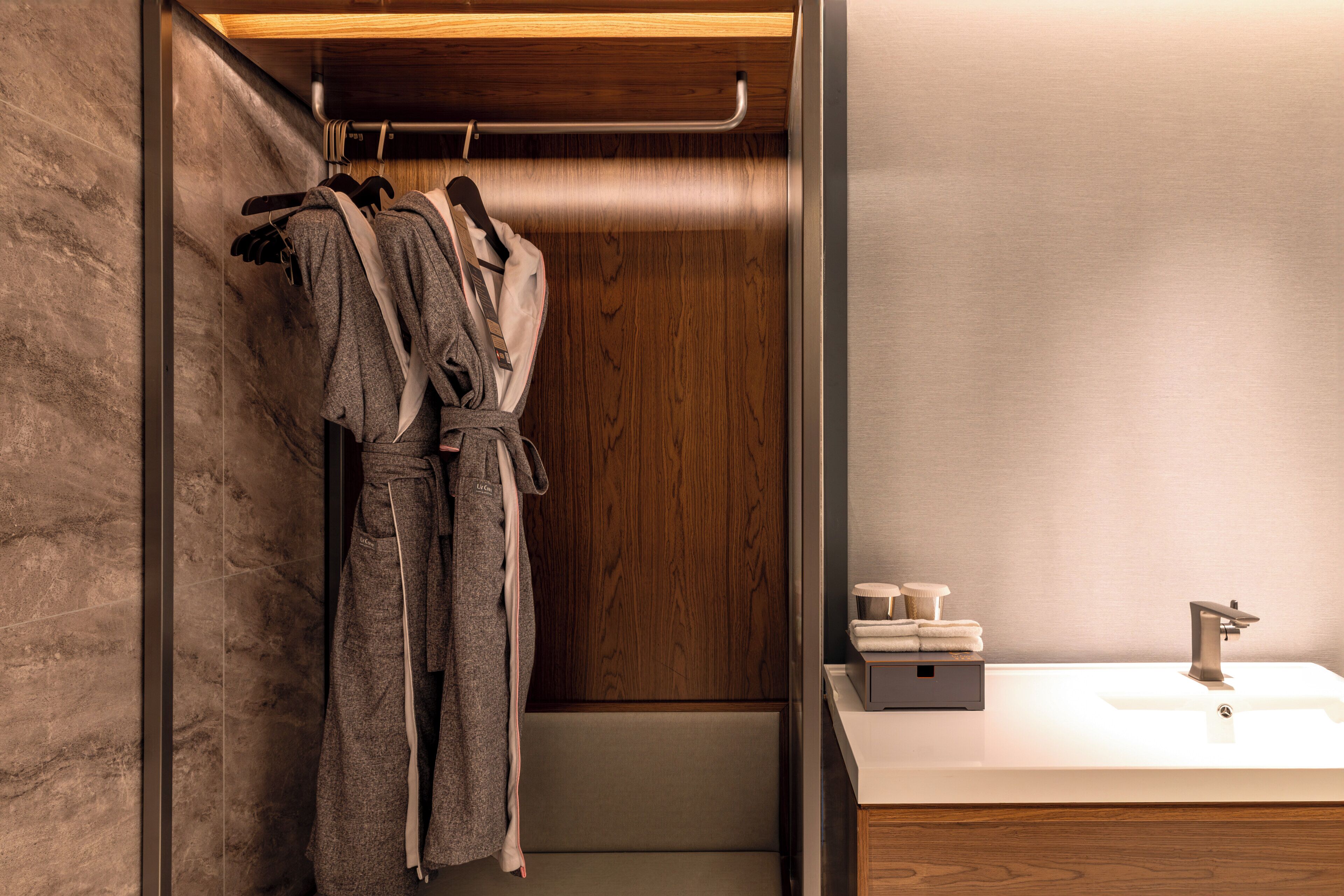 Une salle de bain moderne avec un meuble-lavabo en bois, un évier et un peignoir suspendu à un porte-serviettes.