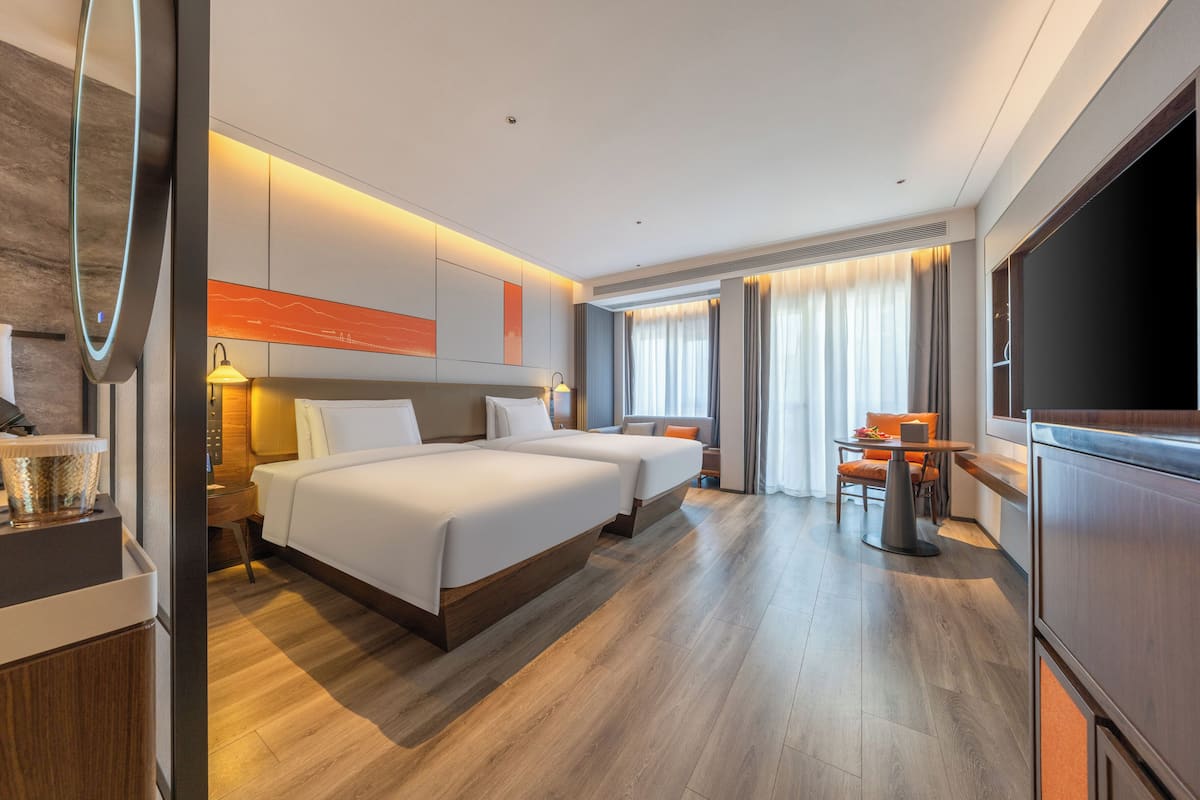 Une chambre d’hôtel avec deux lits, un bureau, une télévision et un coin repas.