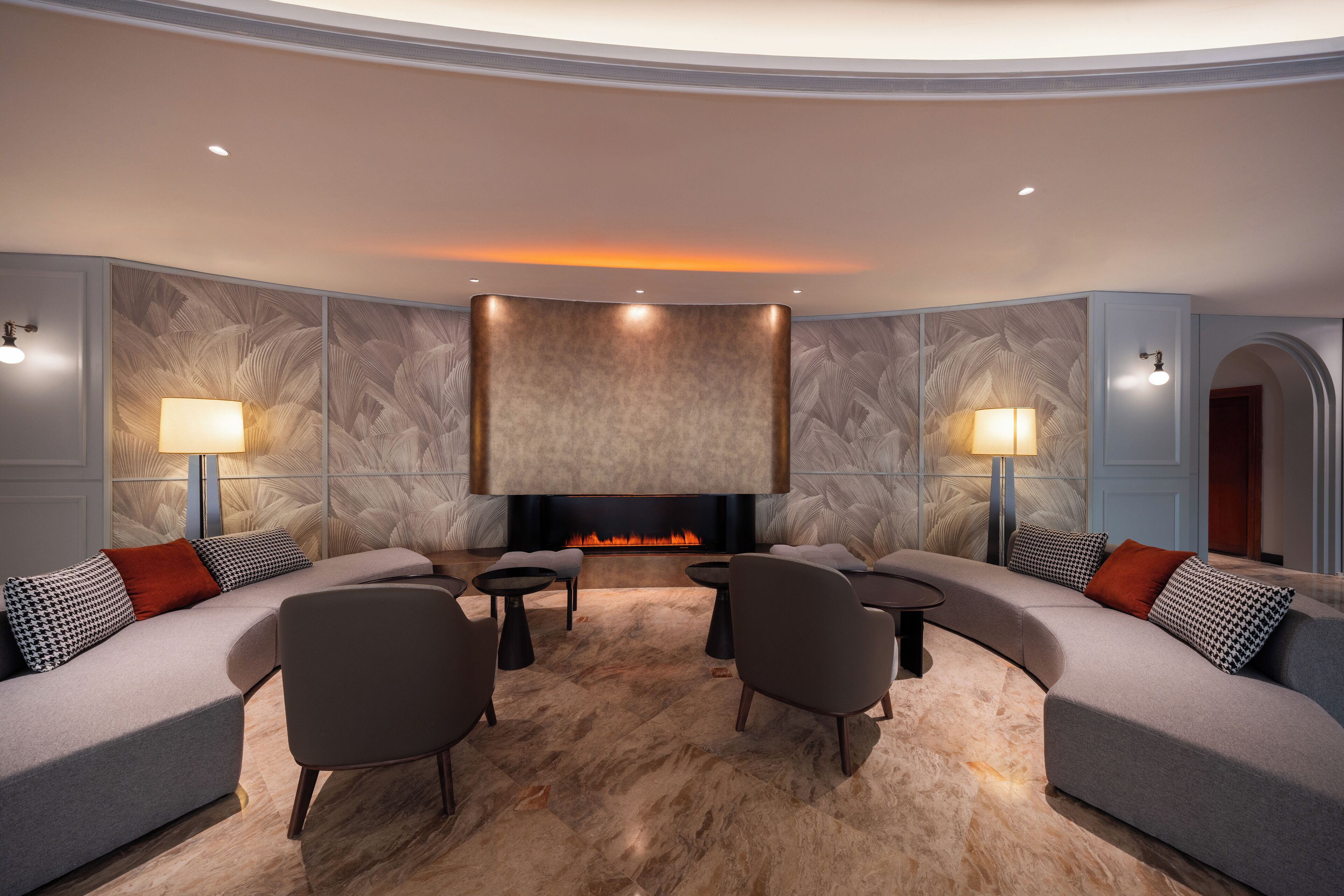 A modern living room with a fireplace, sofas, armchairs, and two side tables.