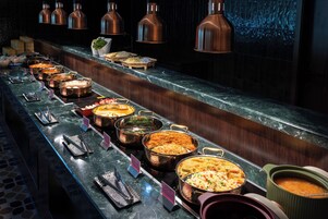 A buffet line with various dishes and a marble countertop.