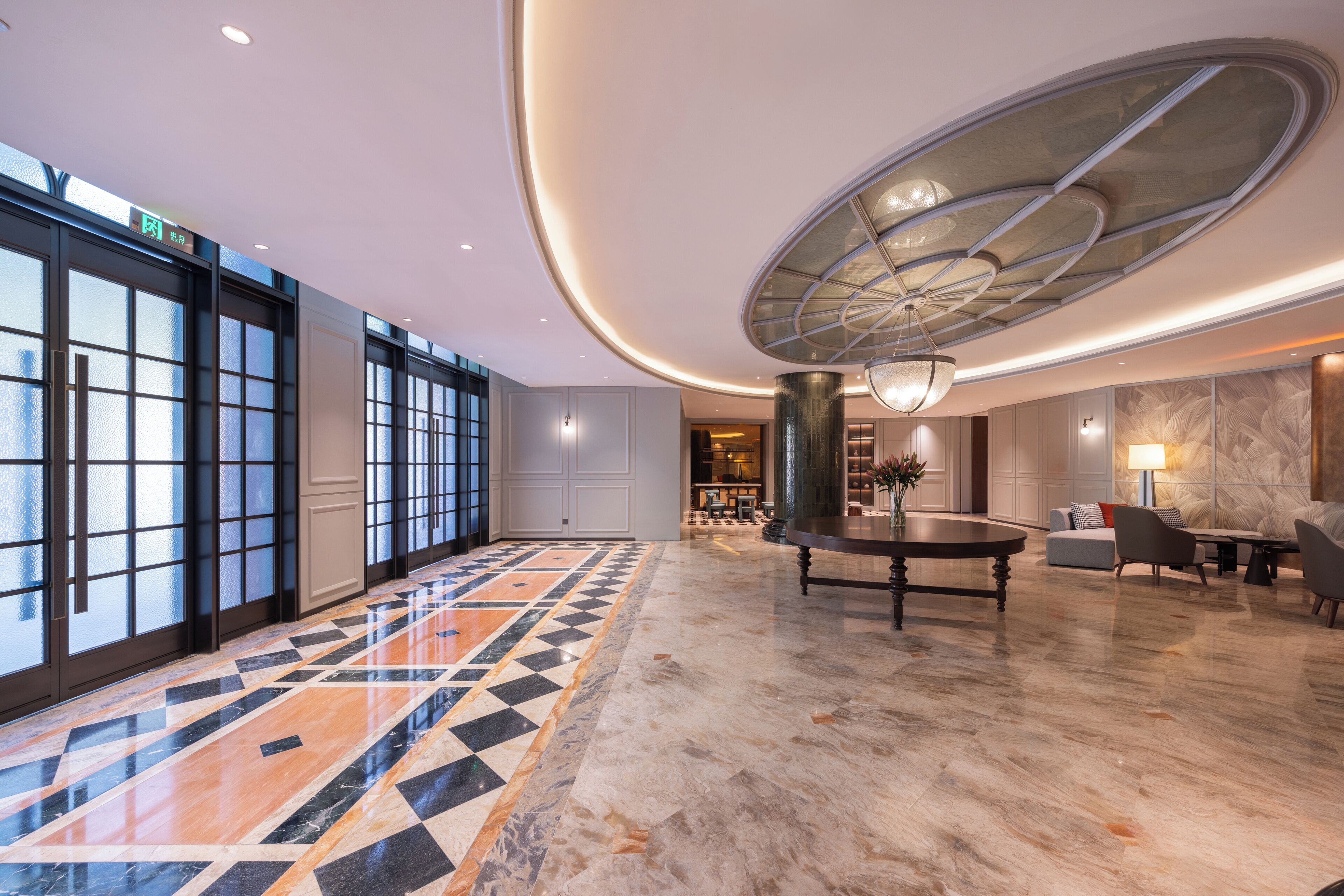 A spacious lobby with a patterned floor, a central table, and seating area.