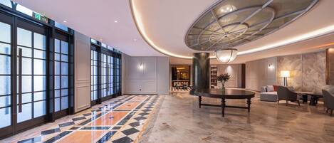 A spacious lobby with a patterned floor, a central table, and seating area.