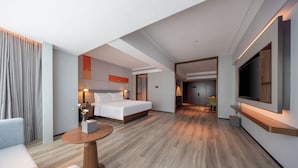 A modern hotel room with a bed, a seating area, a TV, and a desk. - UrCove by HYATT Zhuhai Gongbei Port (Zhuhai)
