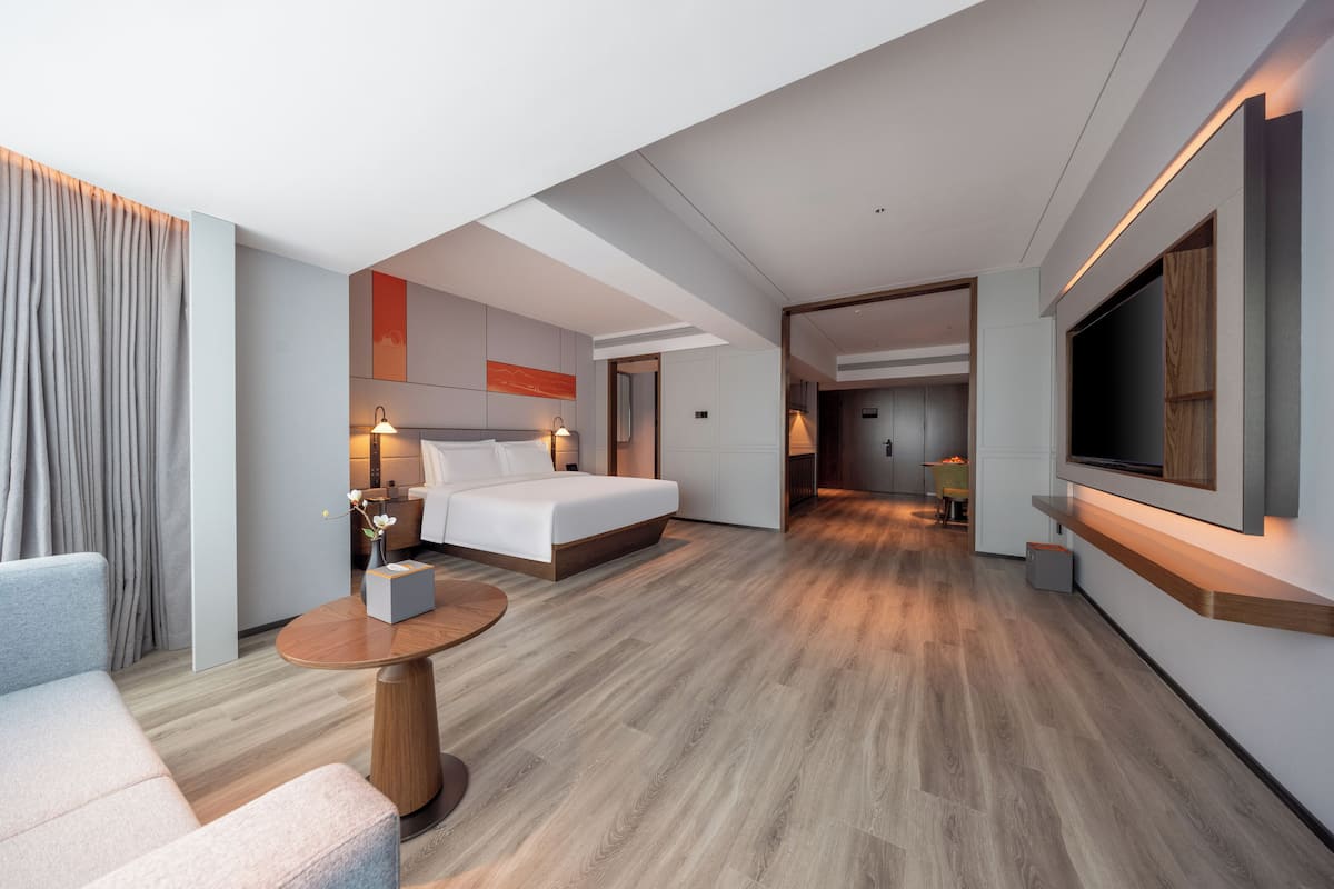 Une chambre d’hôtel moderne équipée d’un lit, d’un coin salon, d’une télévision et d’un bureau.