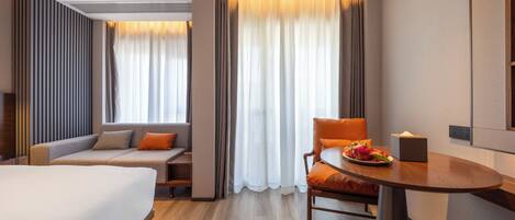 Una habitación de hotel con una cama, un sofá, una mesa de comedor y una silla.