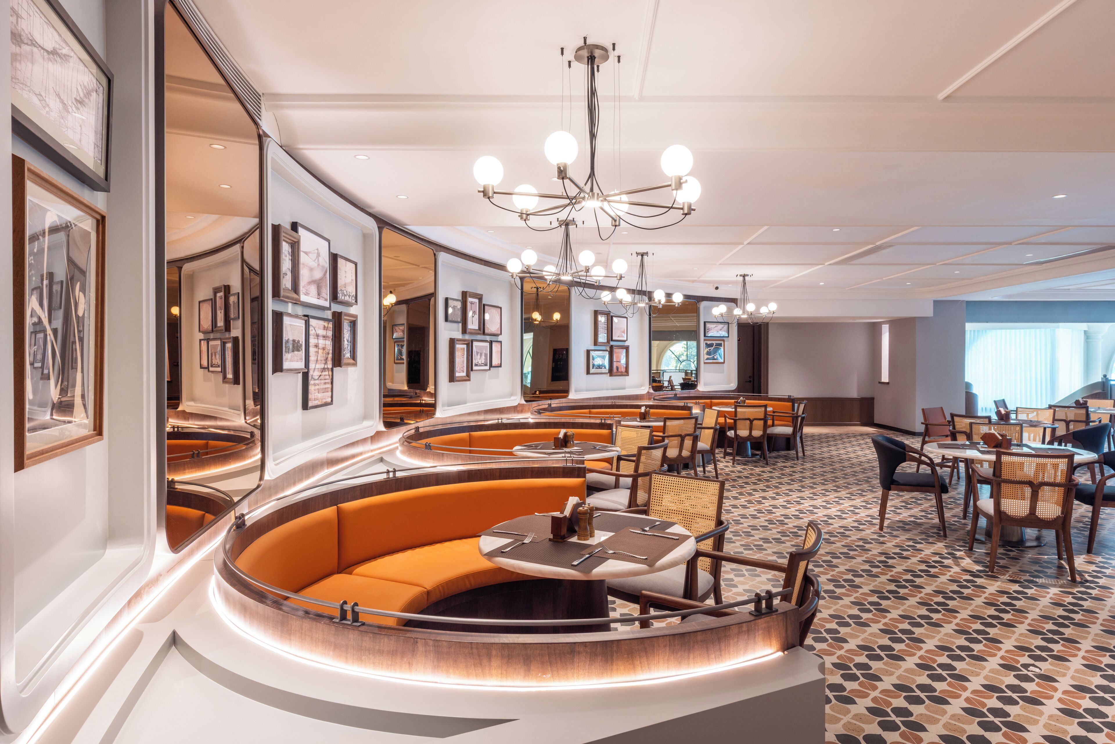 A modern hotel lobby with a curved seating area, framed artwork on the walls, and a chandelier.
