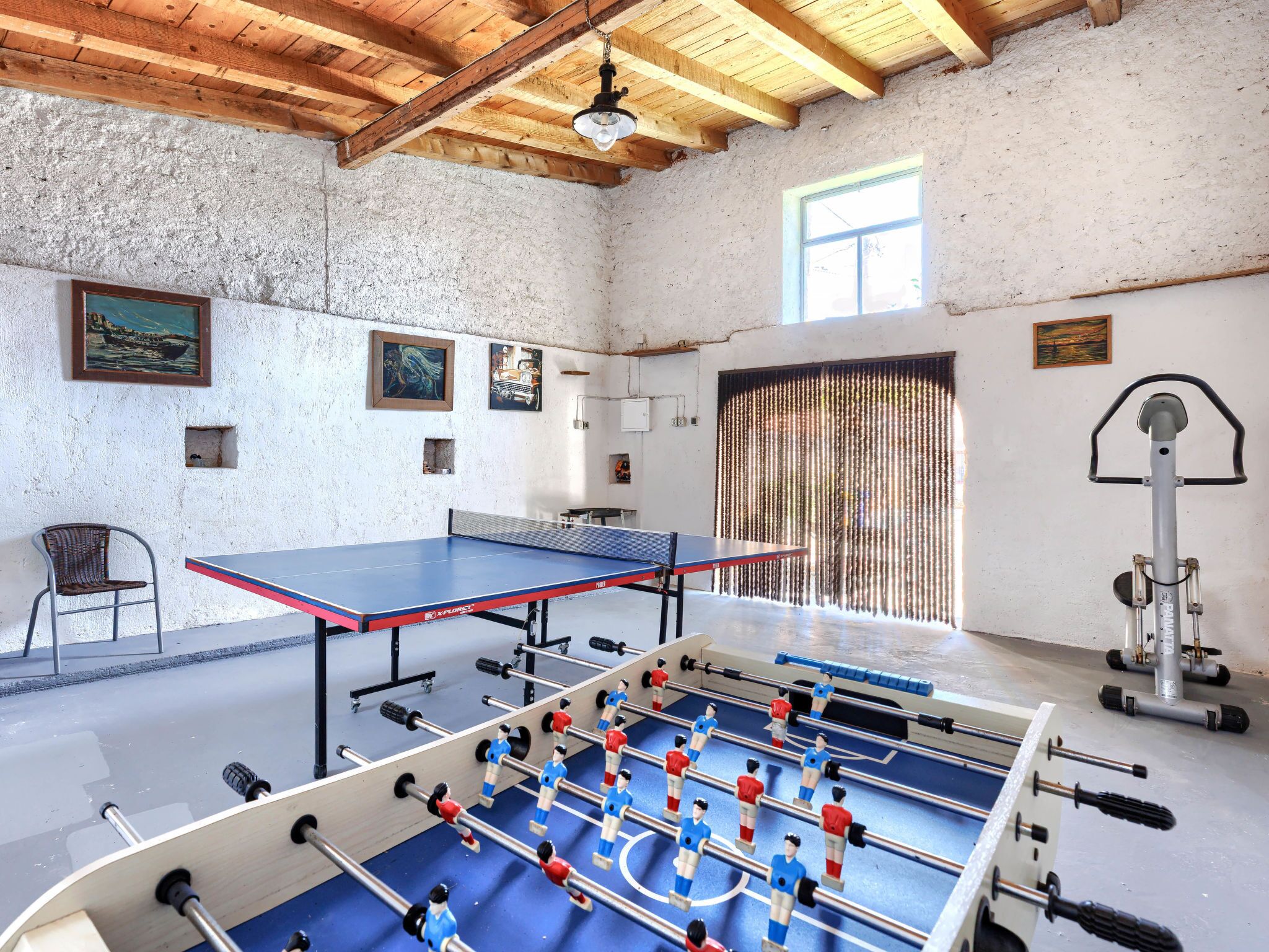 Una habitación con mesa de fútbol de mesa, mesa de ping pong y una bicicleta.