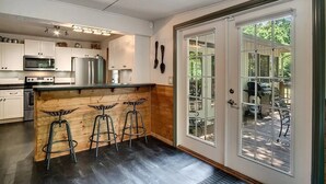 Una cocina moderna con armarios blancos, electrodomésticos de acero inoxidable y una isla de madera con taburetes de bar.