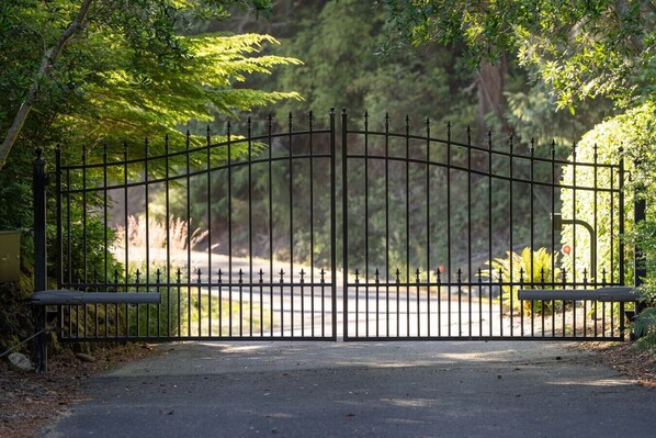 A gated entrance to a park with a paved path leading through.