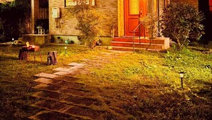 A two-story house with a stone facade, a red door, and a small porch with steps leading up to it. - In a quiet, green environment, with free parking, your room is in the middle of the ocean, you have your own spacious wooden room, a spacious living room with outdoor seating, and your own private garden with a roast fireplace. (由布市湯布院町川上)