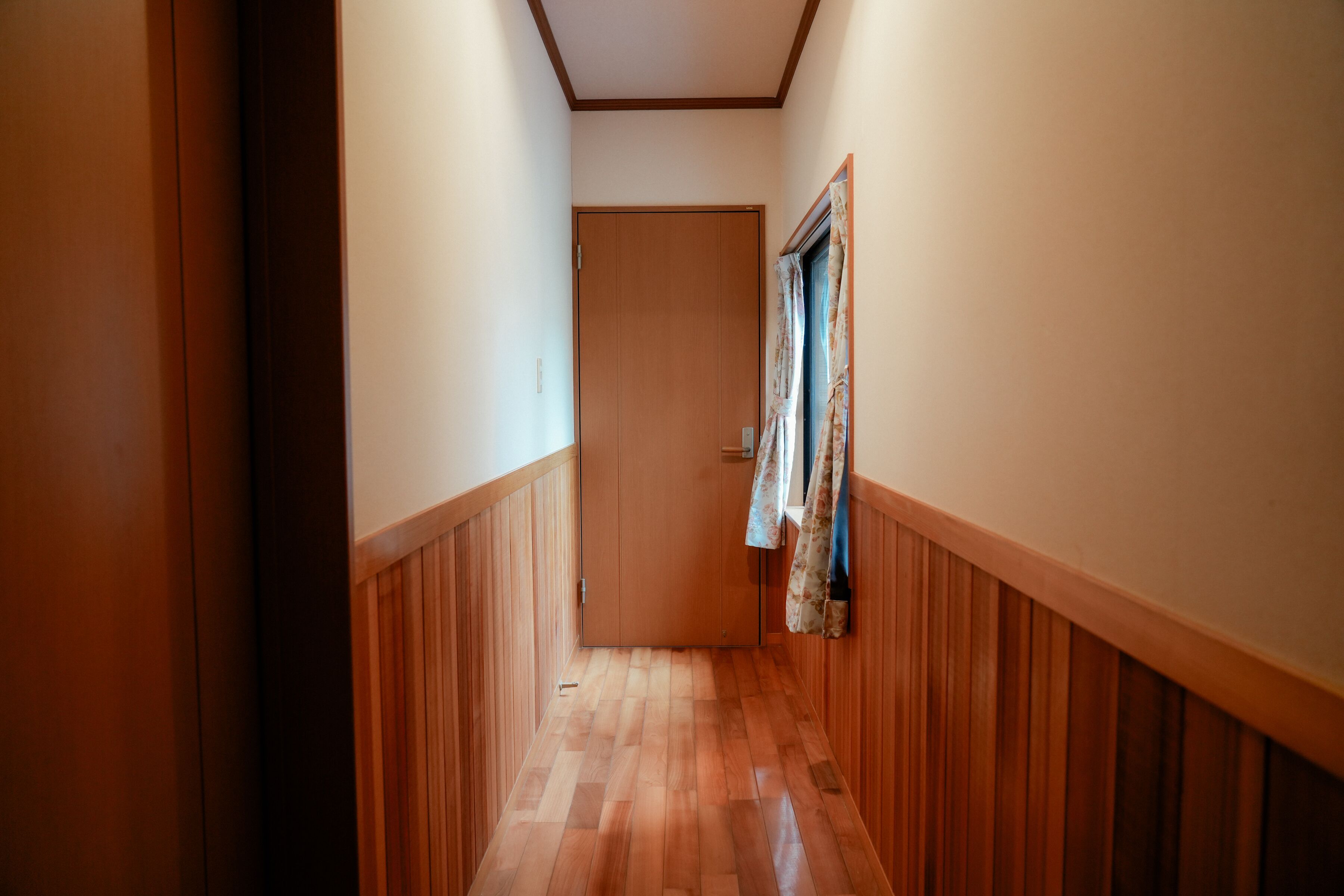 A narrow hallway with wooden paneling on the walls and a wooden floor.
